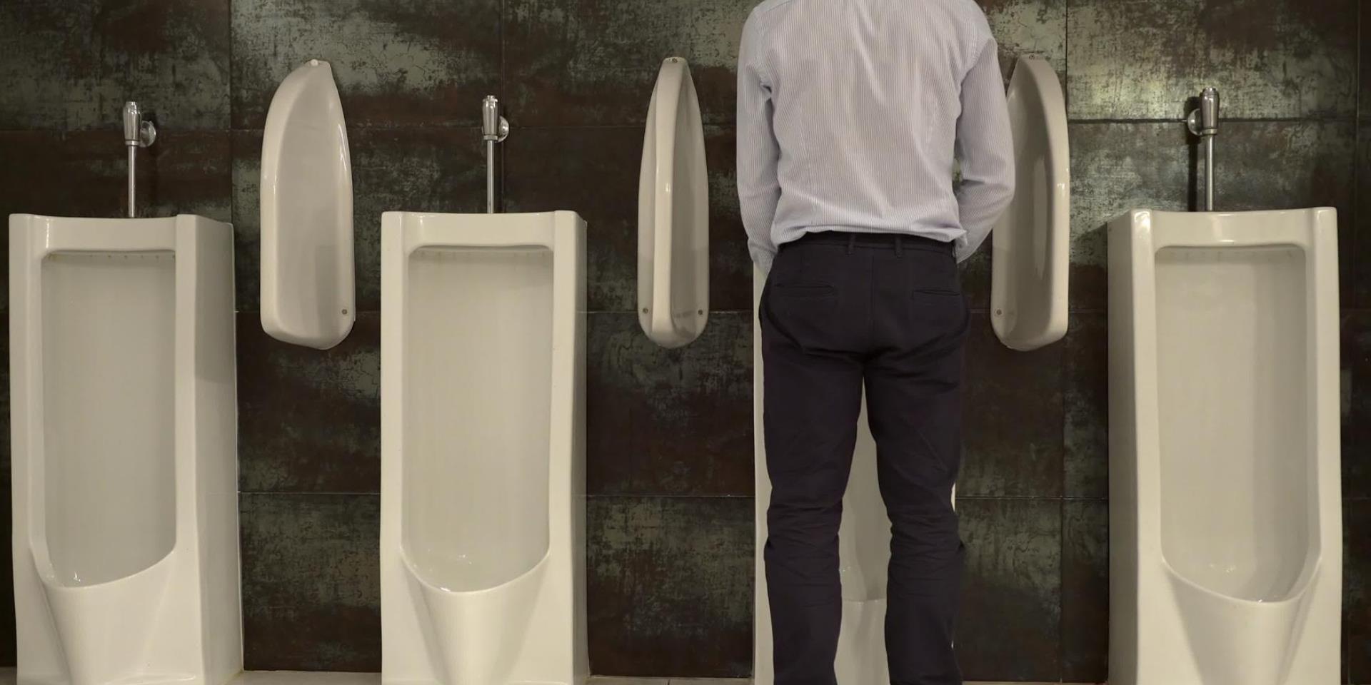 גבר מטיל שתן בשירותים ציבוריים