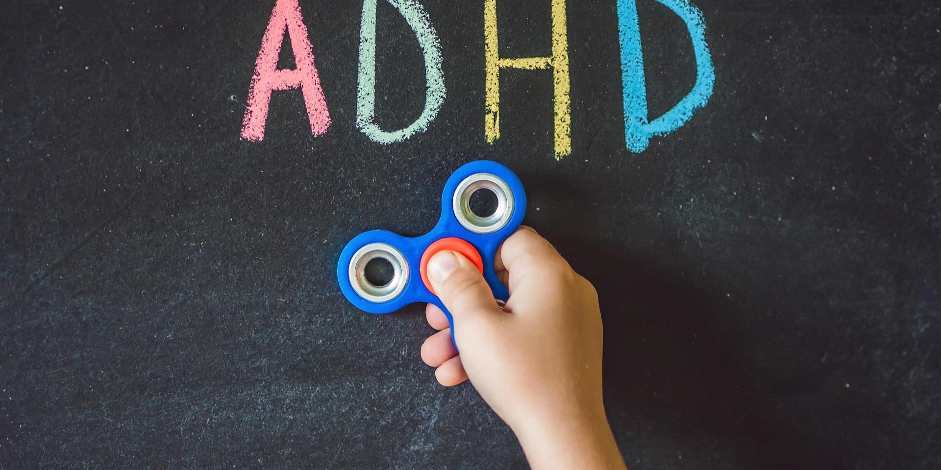 ילד מצמיד ספינר ללוח שעליו כתוב ADHD